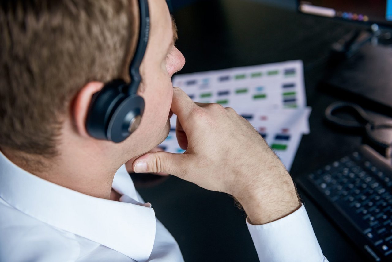 Mitarbeiter mit Headset prüft eine ausgedruckte Prozessübersicht