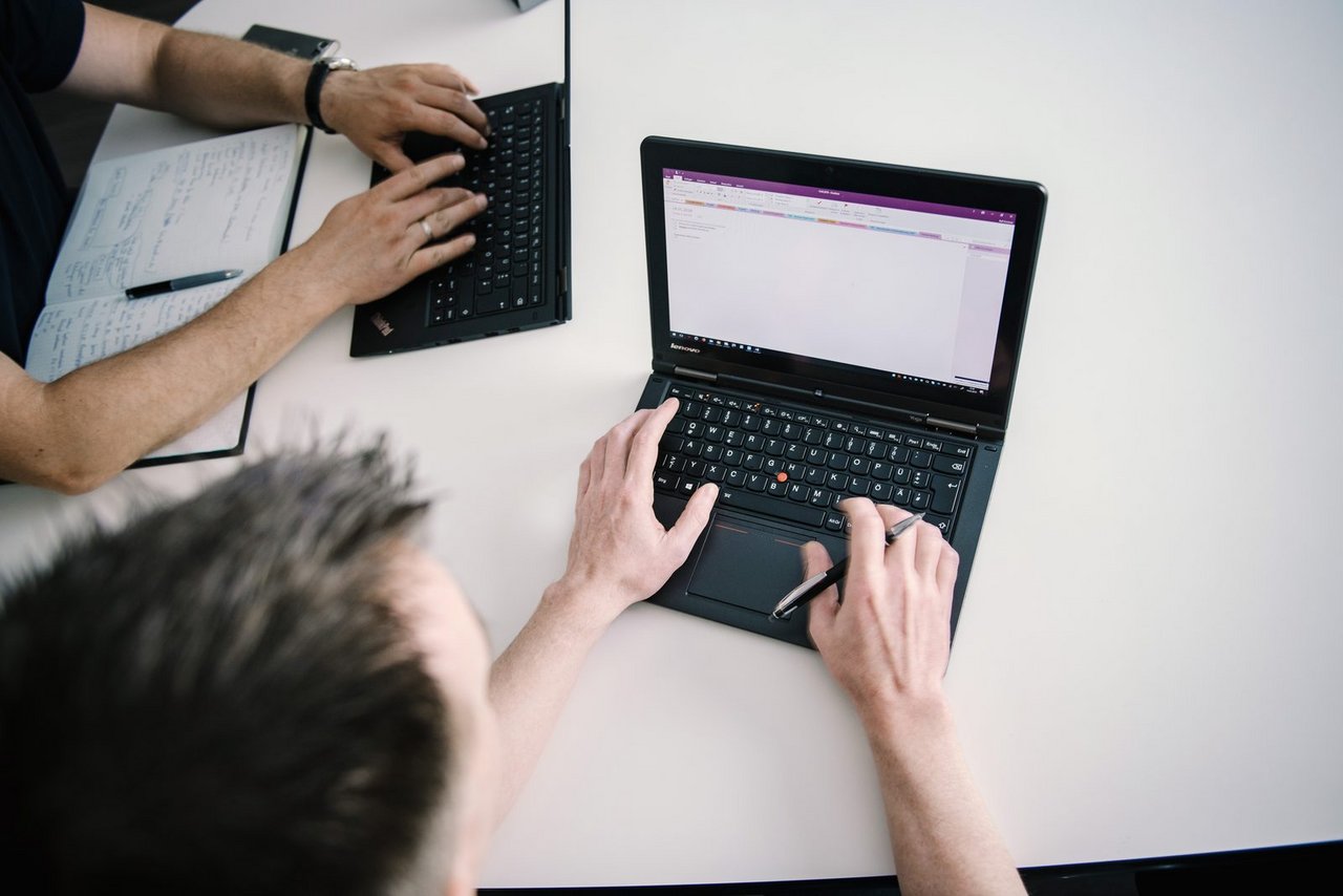 Zwei Mitarbeiter arbeiten am Besprechungstisch mit Laptop und Notizen