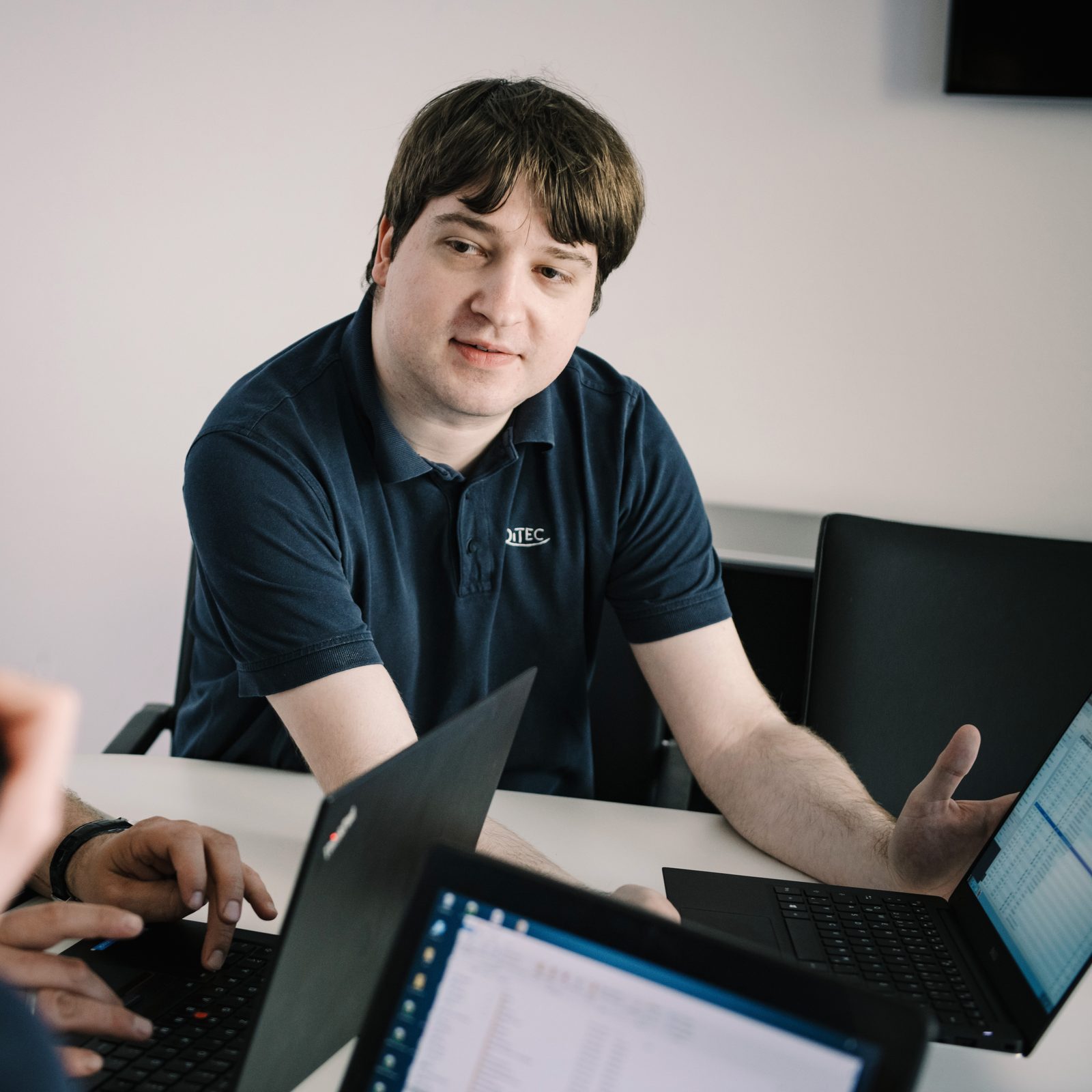 Mitarbeiter erklärt im Gespräch am Tisch mit Laptops